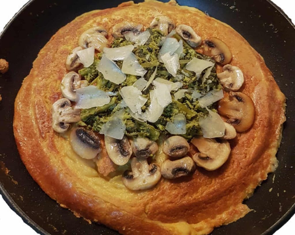Nohut unlu vegan omlet, dilimlenmiş mantar, brokoli ve peynir ile servis ediliyor