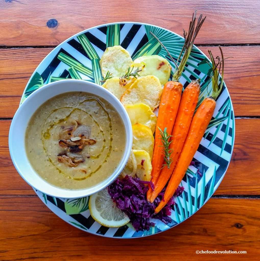 red lentil soup is served with baked onions, carrots and potatoes and lemon slices