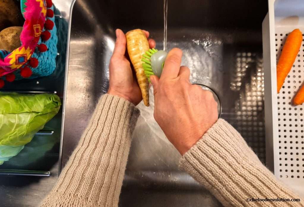 due mani che lavano con una spazzola una pastinaca