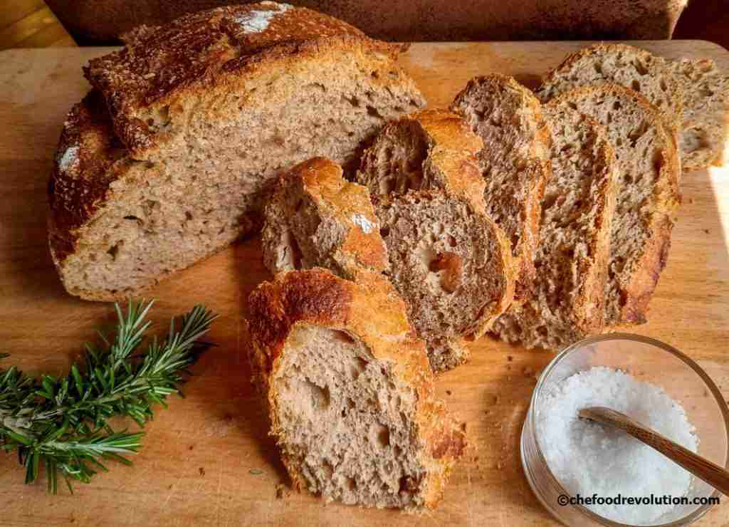 mezza pagnotta di pane integrale con lievito madre alcune foto disposte su un tagliere di legno