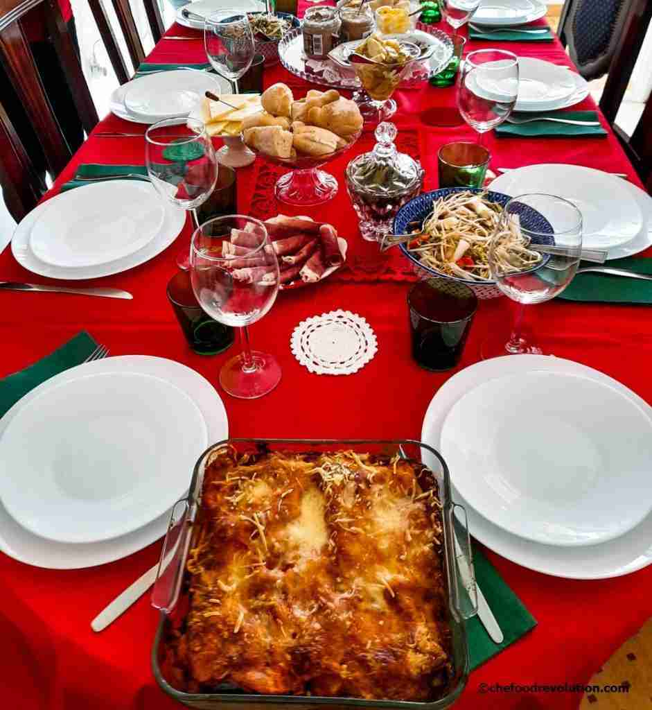 beautiful and colourful Christmas table set with a red tablecloth and laid with various dishes