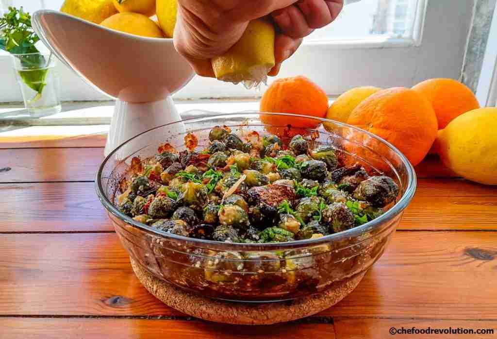 A hand squeezing a lemon over a salad of Brussels sprouts to increase the iron absorption