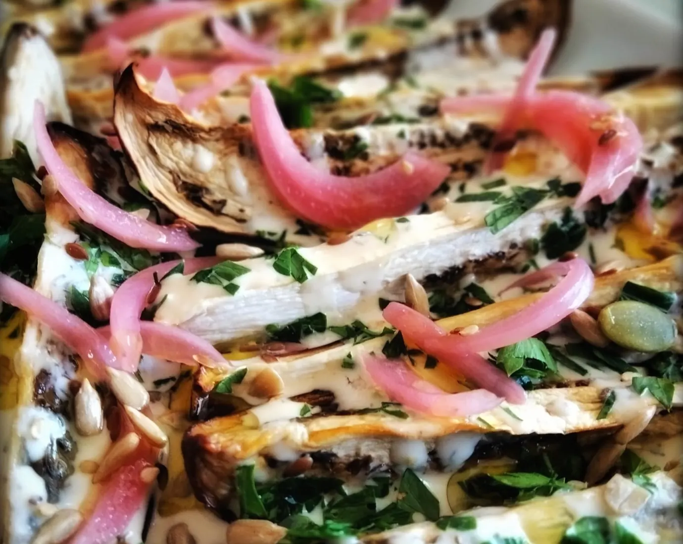 Delicious grilled eggplant with tahini and red onions served with parsley